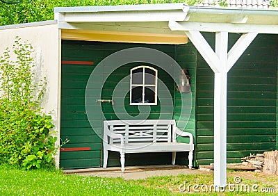 A light green and wooden small shed, gardenhouse, with a bench some tools around it Stock Photo