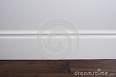 Light matte wall, white baseboard and tiles immitating hardwood flooring Stock Photo