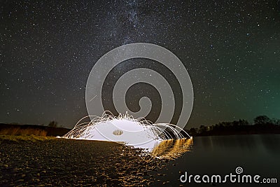 Light painting art concept. Spinning steel wool in abstract circle, firework showers of bright yellow glowing sparkles in Stock Photo