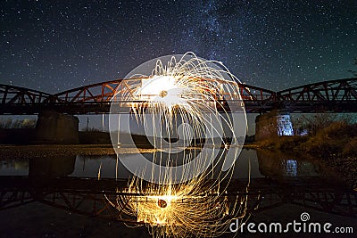 Light painting art concept. Spinning steel wool in abstract circle, firework showers of bright yellow glowing sparkles on long br Stock Photo
