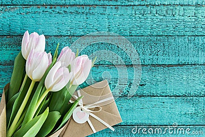 Light pink tulips bouquet and envelope on turquoise wooden tabletop with copy space Stock Photo