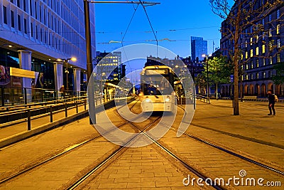 Light rail yellow tram in the city center of Manchester, UK in the evening Editorial Stock Photo