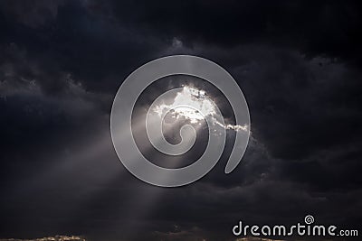 Beaming rays of light break through dark menacing clouds Stock Photo