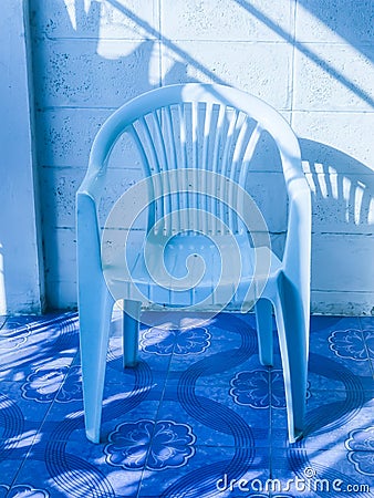 The light reflects on the blue chairs beside the wall. Stock Photo