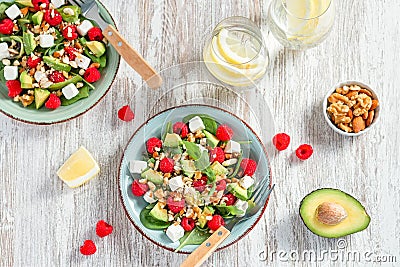 Light salad with raspberry, baby spinach, feta cheese, avocado and walnuts, top view. Fresh original summer salad with lemon water Stock Photo