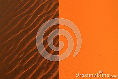 Light and shadow symmetrically dissect an orange sand dune. Stock Photo