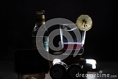 light shot on black background showing glass fileld with mulled infused wine gin with lemon wedge and bottle of tonic on Editorial Stock Photo