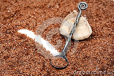 Dark gray metal spoon lies against a background of brown flax seeds. healthy seeds full of vitamines. Stock Photo