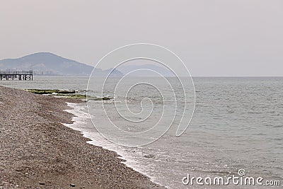 Light surf on a sandy beach against the backdrop of a pier and distant mountains, evening, Alanya, April 2021 Stock Photo