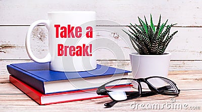 On a light table are notepads, a potted plant, black-framed glasses and a white cup with the text TAKE A BREAK Stock Photo
