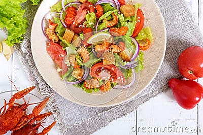 Light tasty salad with meat of a cancer, shrimps, lettuce, garlic croutons, tomatoes, red onions Stock Photo