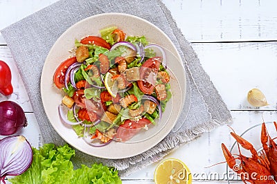 Light tasty salad with meat of a cancer, shrimps, lettuce, garlic croutons, tomatoes, red onions on a white background. Stock Photo