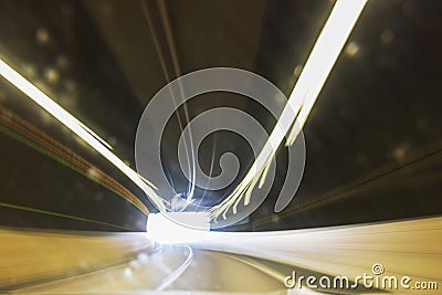 Light trails in tunnel leading towards bright exit, creating a sense of speed and motion. Stock Photo