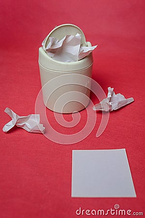 Light trash bin on a red background. Closeup of crumpled sheets of paper. White sheet of paper for text Stock Photo