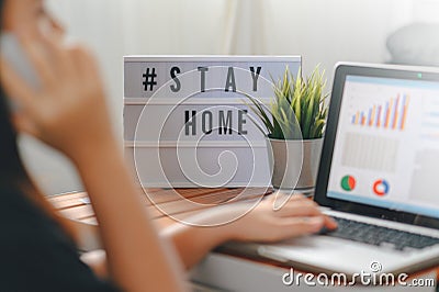 Lightbox with text hashtag STAYHOME glowing in lightand blurred woman working at home. Office worker on quarantine. Home working Stock Photo