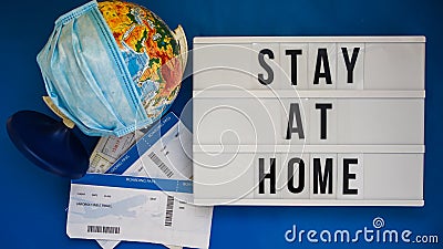 Lightbox with text STAY AT HOME World globe with medical face mask on blue background Stock Photo