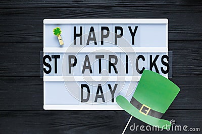 Lightbox with title Happy st Patrick Day and photobooth bow tie beard on wooden sticks on black wooden background. Stock Photo