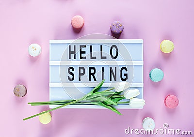 Lightbox with title Hello spring and tender tulips, macaroons on pink background. Decoration, spring background. Top view Stock Photo