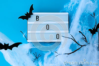 Lightbox with word BOO and halloween party decorations. Bats on dry tree branch with spider net for Halloween on blue Stock Photo