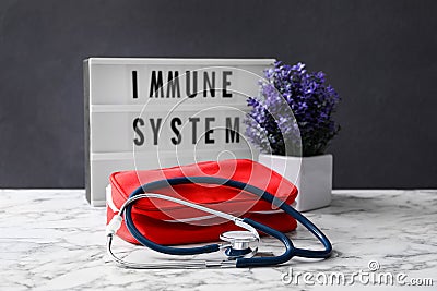 Lightbox with words Immune System, flowers and first aid kit on white marble table Stock Photo