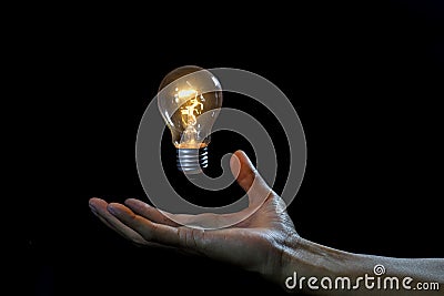 Lightbulb on hand black background, magic idea energy concept Stock Photo
