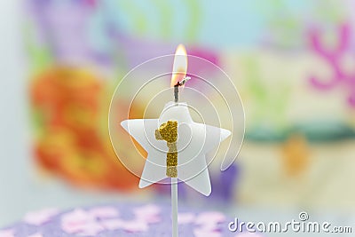 Lighted birthday candle in star shape with blurred background. 1 year anniversary, deep sea theme. Celebration, party and joy Stock Photo