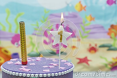 Lighted birthday candle in star shape with blurred background. 1 year anniversary, deep sea theme. Celebration, party and joy Stock Photo