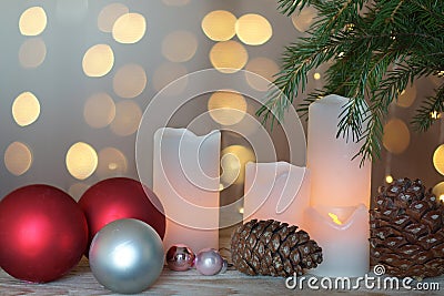 Lighted candles, cones and festive balls next to a Christmas tree and garland in the background Stock Photo