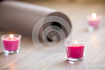 Lighted pink candle and rolled brown yoga, pilates mat on the fl Stock Photo