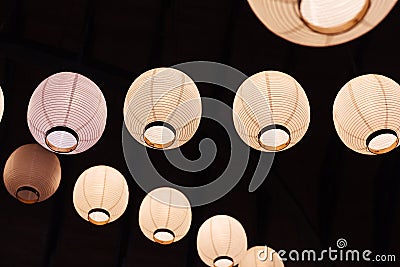 Lighted white paper lamps on ceiling in black background Stock Photo