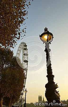 lightened old street lamp on the bank of Thames river during autumn season during sunset Editorial Stock Photo