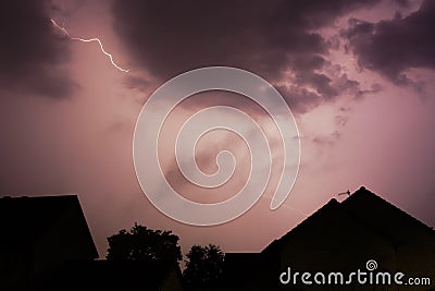 Lightening bolt over houses in the middle of a storm Stock Photo