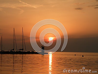 Lighthouse at the end of the pier of stones, sunset over the Adriatic Sea, Croatia, Europe.Orange, calm sea, silhouette, reflectio Stock Photo