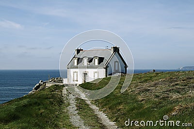 Lighthouse house with green lawn and blue ocean. Brittany, France Stock Photo