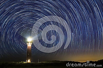 Lighthouse at night with star trails at the center Stock Photo