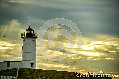 lighthouse Nubble against a dramatic sky background with sun rays and birds in the sky. USA. Maine. Stock Photo