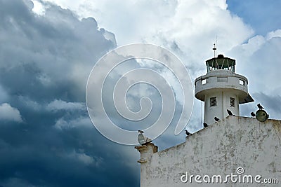 A lighthouse on an old building in Telchac Puerto on the coast of YucatÃ¡n on the Gulf of Mexico, cormorants sitting on the roof Stock Photo