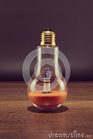 Lighthouse on orange sand in spiral bulb on wooden table Stock Photo