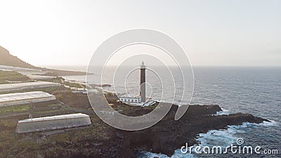 Lighthouse in a rocky cliff and banana tree around on the atlantic ocean. Coastline in the sunset. Light orientation to navigate Stock Photo