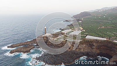 Lighthouse in a rocky cliff and banana tree around on the atlantic ocean. Coastline in the sunset. Light orientation to navigate Stock Photo