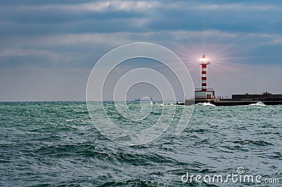 Lighthouse searchlight beam through marine air. Lighthouse In Stormy Landscape - Leader And Vision Concept Stock Photo
