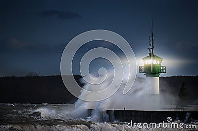 Lighthouse during storm in splashing spray at night on the Baltic Sea, Travemuende in the Luebeck bay, copy space Stock Photo