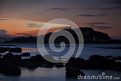 Lighthouse at sunset with light beam Stock Photo