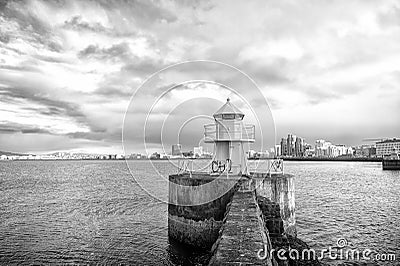 Lighthouse tower on stone pier in reykjavik, iceland. Lighthouse in sea. Seascape and skyline on cloudy sky Stock Photo