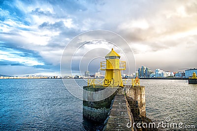 Lighthouse tower on stone pier in reykjavik, iceland. Lighthouse in sea. Seascape and skyline on cloudy sky. Architecture structur Stock Photo