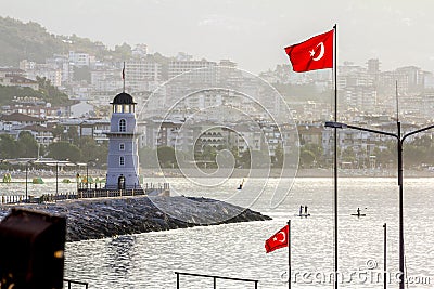 Lighthouse and Turkish flags in the Harbor in Alanya in Turkey at dawn Stock Photo