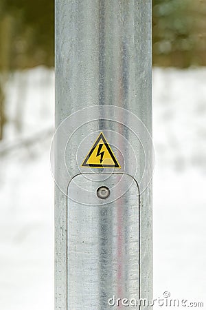 Lighting pole in the city. Electricity service door. Pasted yellow warning sign with lightning. High voltage Stock Photo