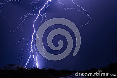 Lightning bolt strikes a hillside during a powerful storm. Stock Photo