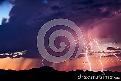 Lightning bolts strike from a storm at sunset Stock Photo