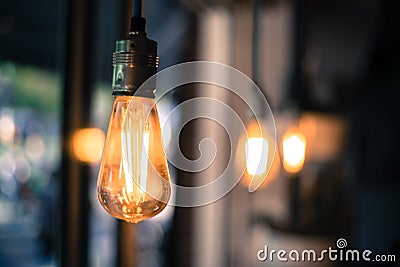 Lightning in the restaurant: Close up of a hanging, orange lightbulb Stock Photo